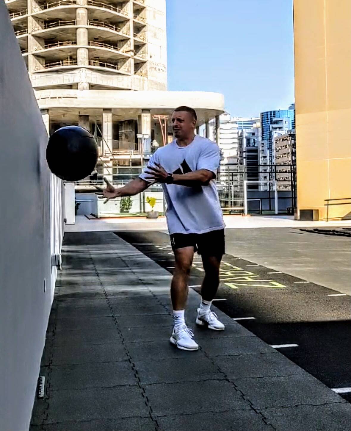 Christopher Mallett performing a med-ball throw during rooftop conditioning work in Dubai